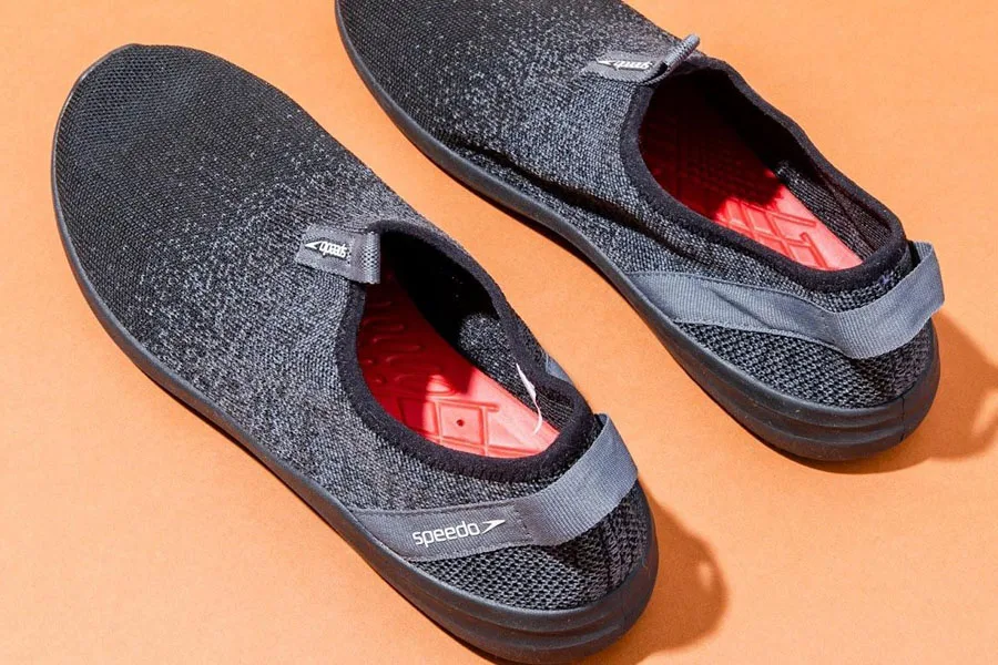 Sepasang sepatu bot air tertutup berwarna hitam dengan sol dalam berwarna merah