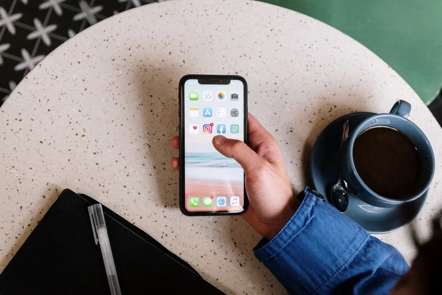 Eine Person hält ein Smartphone in der Hand, während sie Tee trinkt