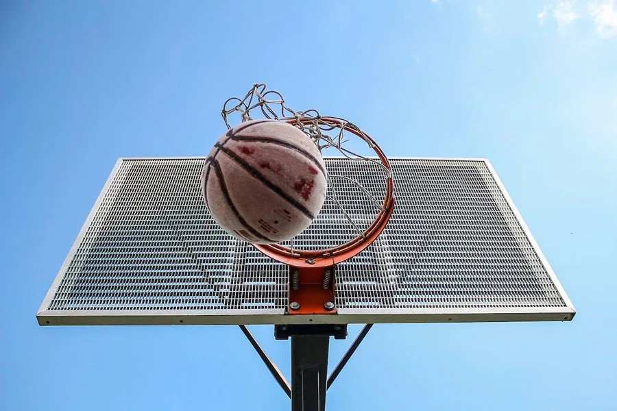 A rubber basketball going through a basketball hoop