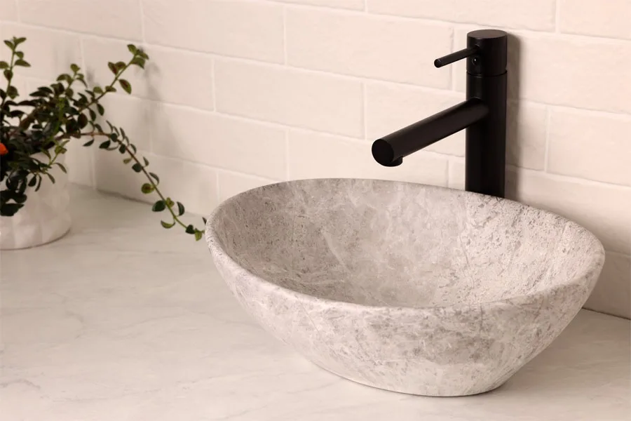 Un lavabo en pierre sur un comptoir en marbre