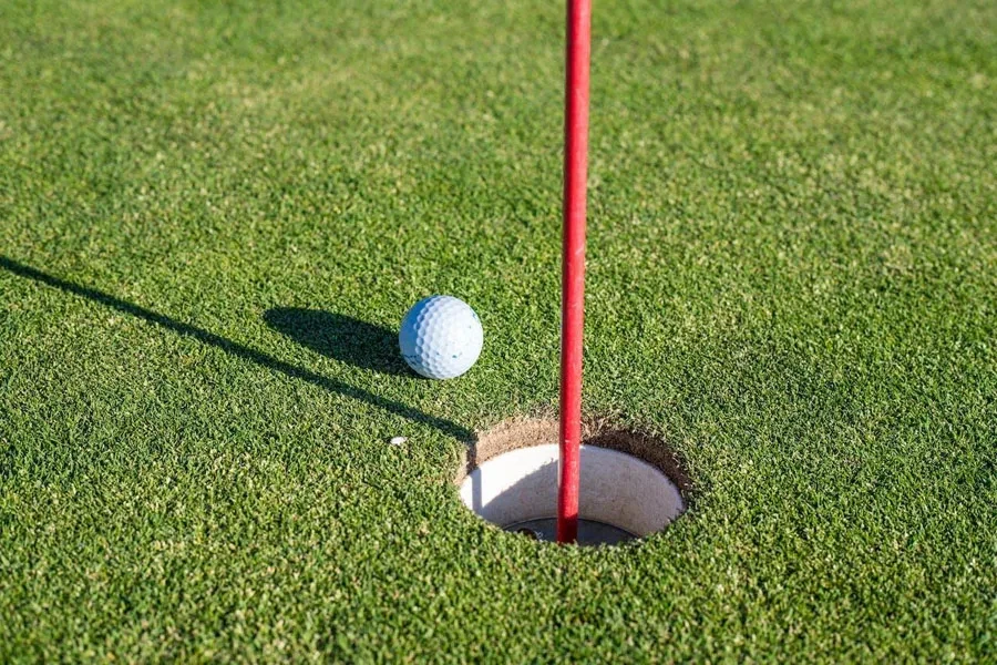 Una pelota de golf de tres piezas cerca de un hoyo.