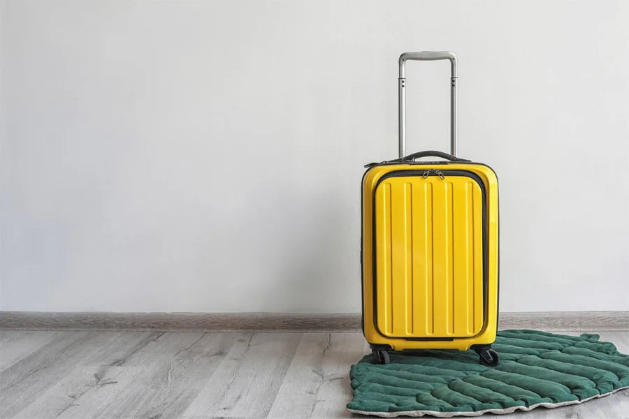 Желтый чемодан на зеленом коврике в форме листа.