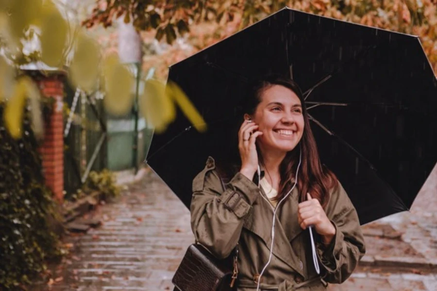 Eine junge Frau hört im Regen mit Headset Musik