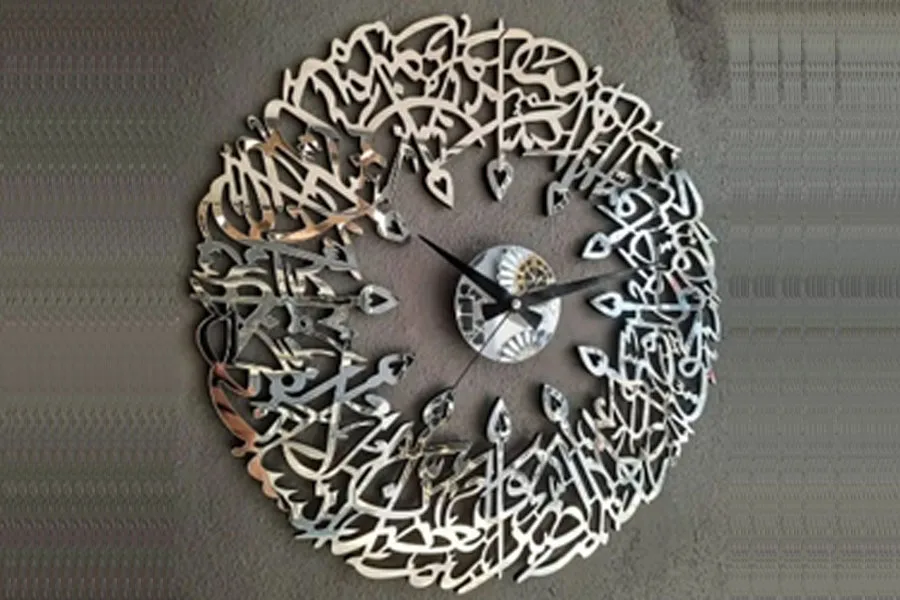 Um relógio de parede islâmico ornamentado em metal prateado, espelho e vidro