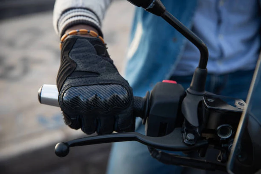 Sarung tangan sepeda motor berwarna hitam yang dikenakan oleh pria di atas sepeda motor