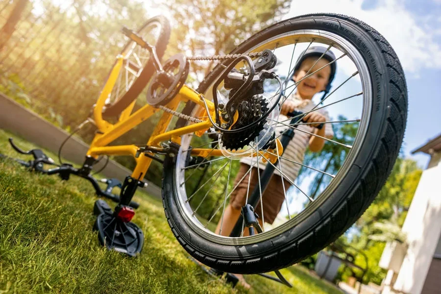 Boy is inflating bicycle tire with air pump at home backyard.