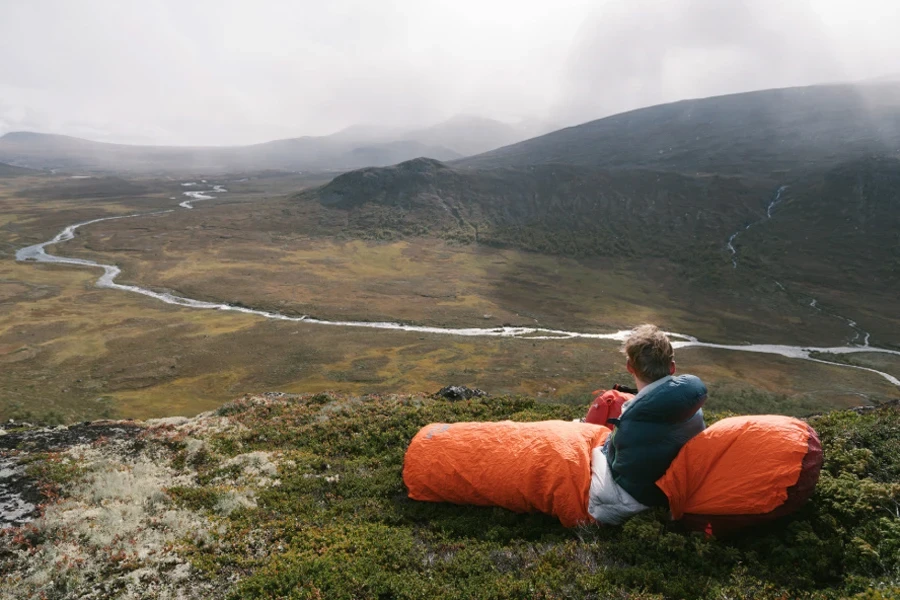 Camper using a bivy bag on a hill