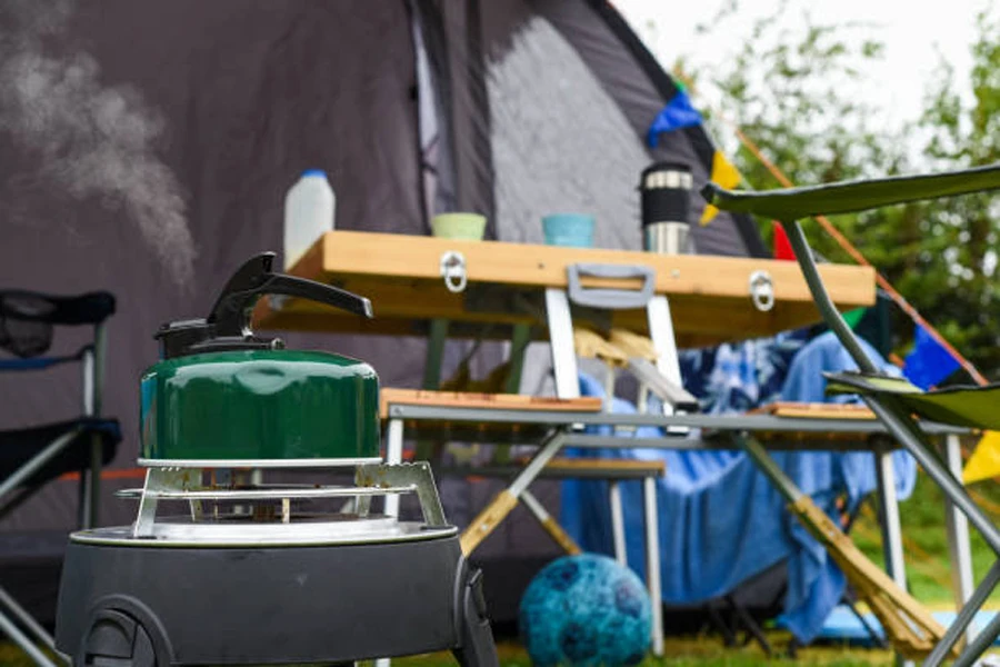 Sitio de camping acondicionado con sillas y barbacoa portátil.