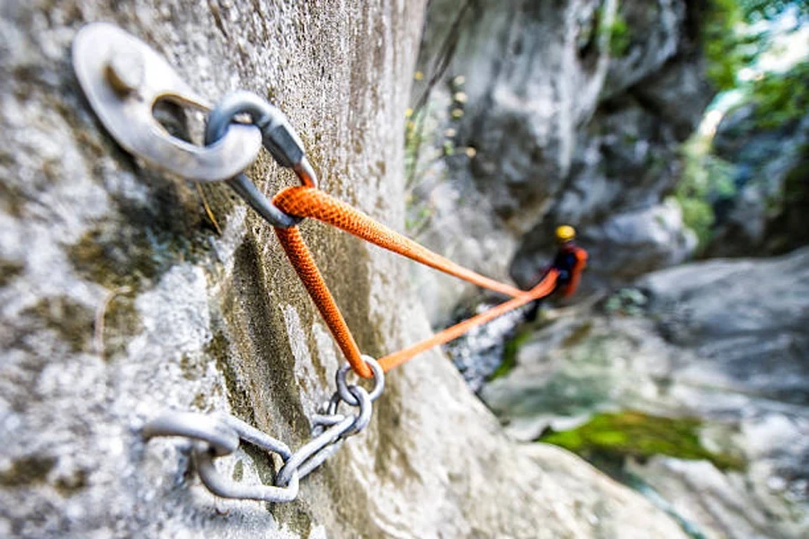 Climbing carabiner attached to hook in rock face