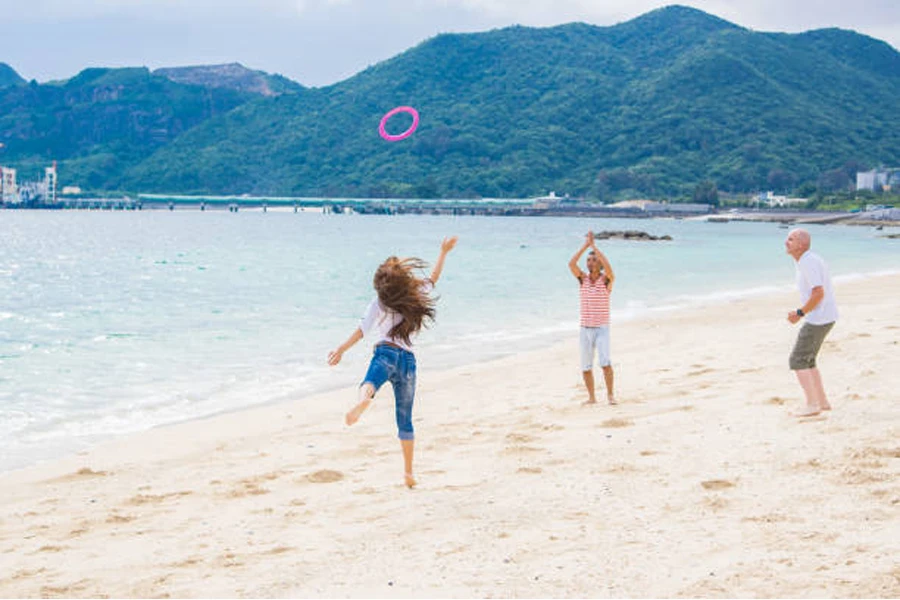 Familia jugando con anillo volador púrpura en la playa de arena