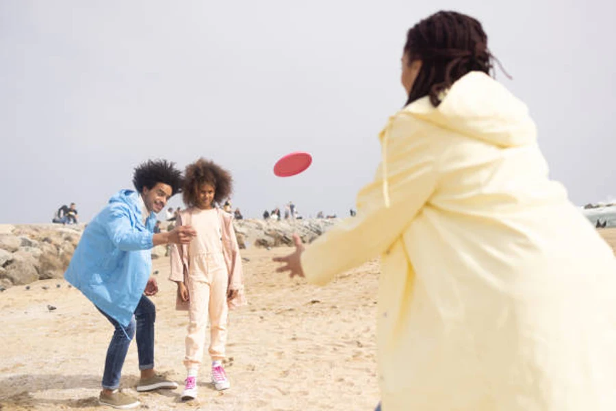 Familia jugando con mini frisbee rojo en la playa