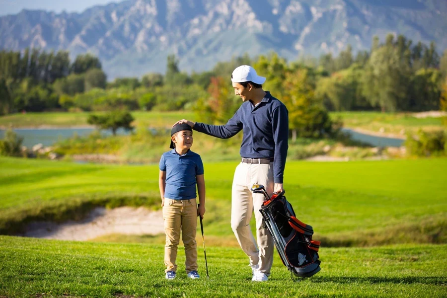 Padre e figlio camminano e parlano su un campo da golf soleggiato