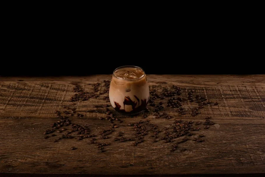 Verre de café glacé sur une surface brune avec des grains de café épars