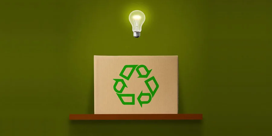 Lâmpada incandescente no ar sobre a caixa de papelão com símbolo de reciclagem verde na prateleira de madeira