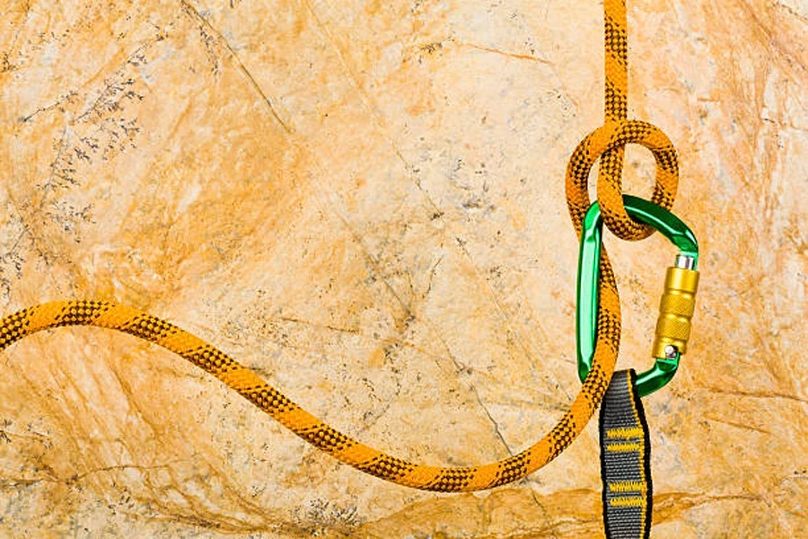 Green locking carabiner attached to orange rope