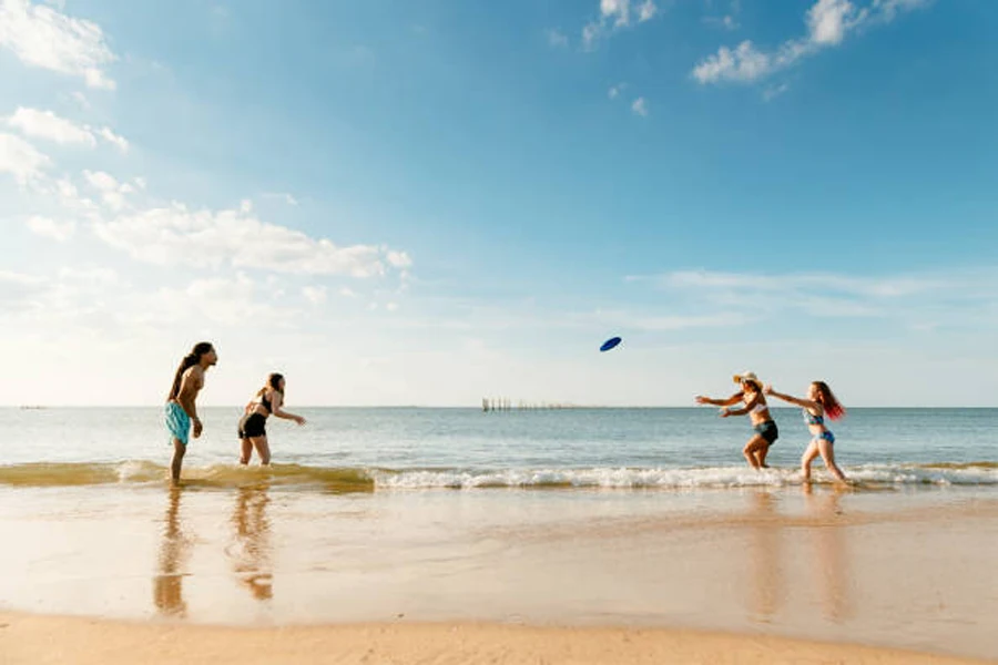Grupo de quatro pessoas jogando frisbee na praia