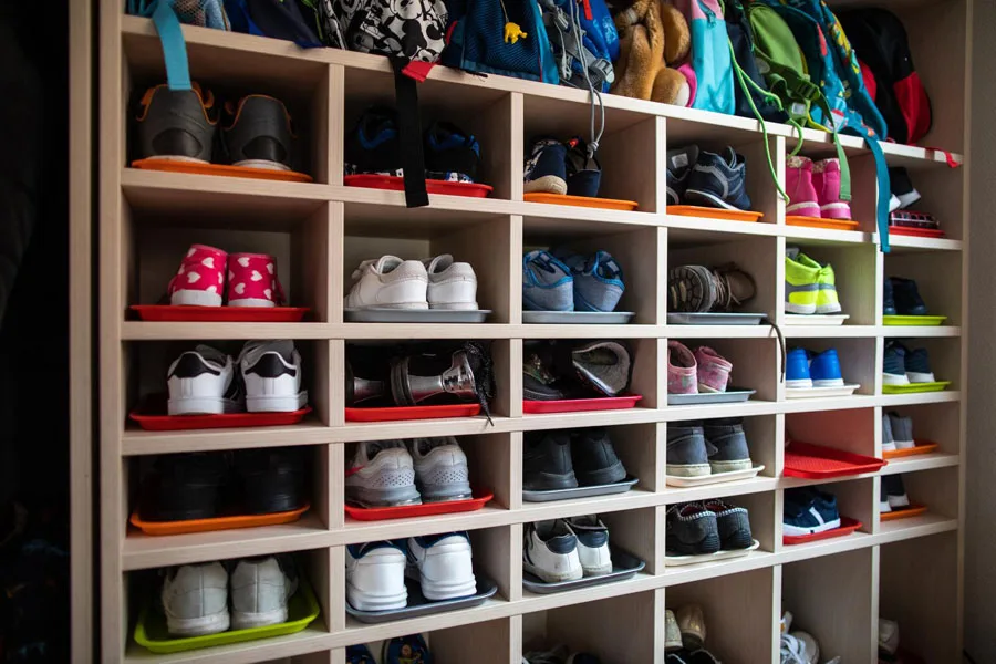 Cubículos de jardín de infantes con zapatos y mochilas.