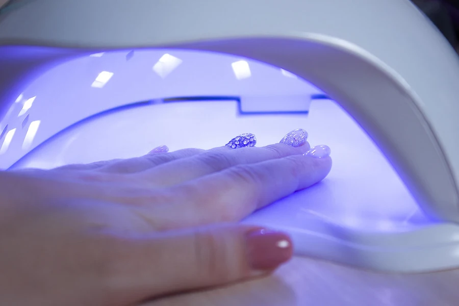 Dame trocknet Nägel in einem UV-Nageltrockner