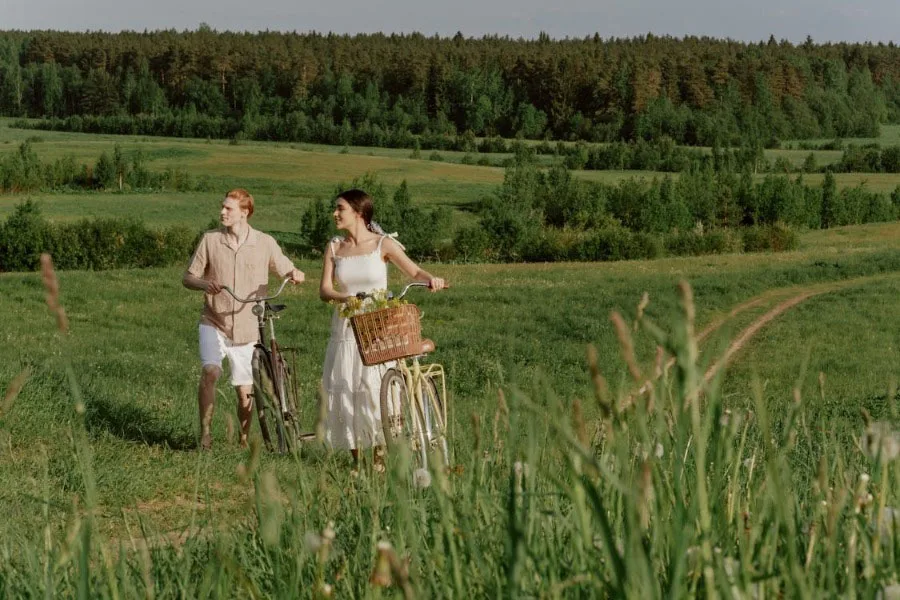 Homem e uma mulher em um campo com suas bicicletas