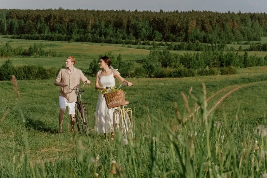 Man and a woman in a field with their bikes