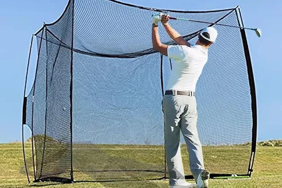 Man in front of large golf cage on grass