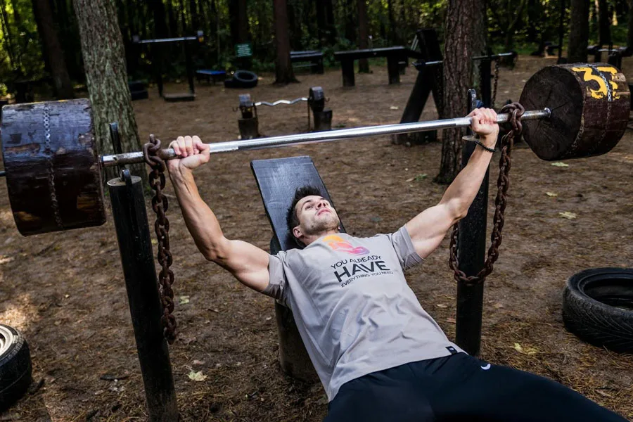 Man in gray top training on a weight bench