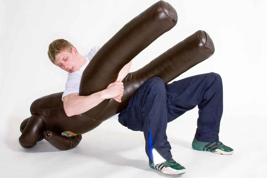 Man practicing takedowns on a brown wrestling dummy