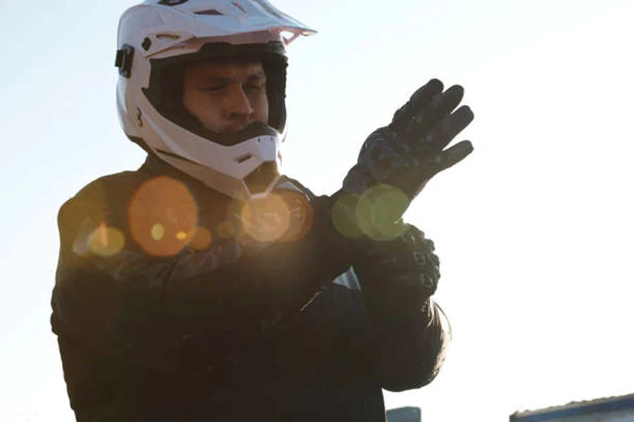 رجل يسحب قفازات دراجة نارية سوداء ويرتدي خوذة بيضاء