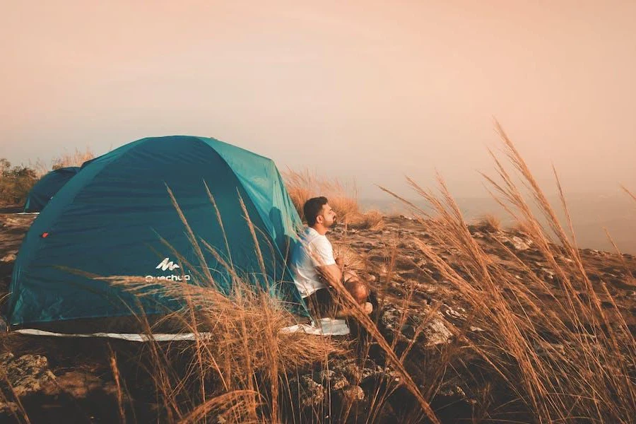 Uomo seduto davanti a una tenda pop-up blu