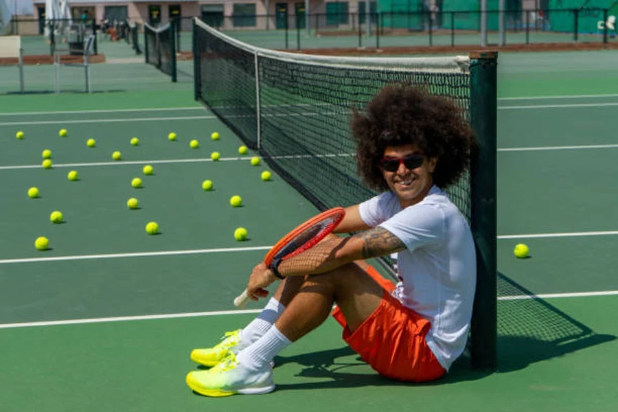 Hombre sentado en una cancha dura verde con zapatos tenis ligeros