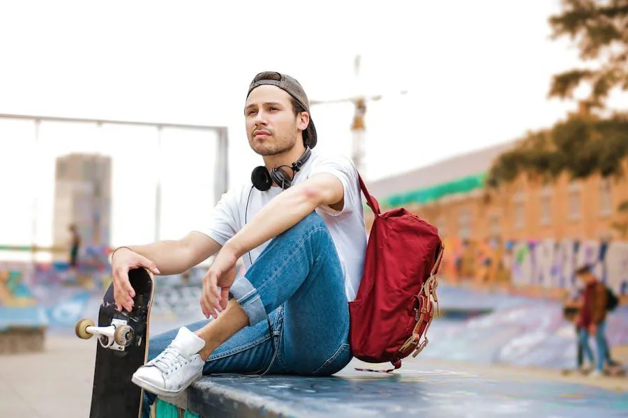 Uomo con uno zaino rosso che tiene uno skateboard