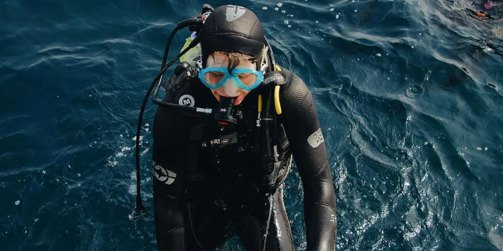 Homme avec des accessoires de plongée sous-marine après la montée