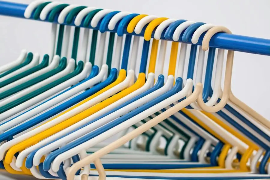  Multi-colored plastic clothes hangers on a rack.