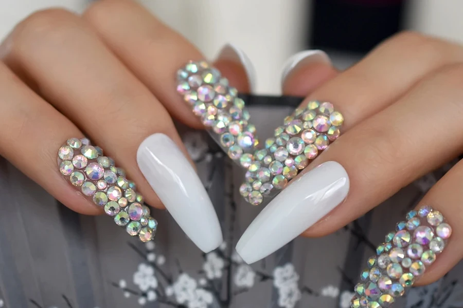 Diamantes de imitación para uñas mezclados con uñas pulidas en blanco.