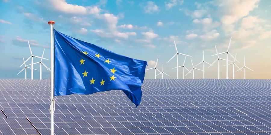 Drapeau officiel de l'Union européenne devant un large éventail de panneaux solaires et d'éoliennes