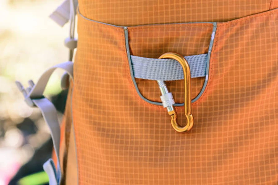 Оранжевый карабин с замком для аксессуаров, прикрепленный к рюкзаку