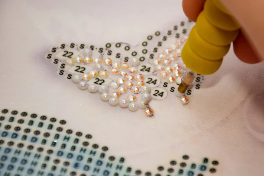 Person applying a rhinestone to a butterfly diamond painting