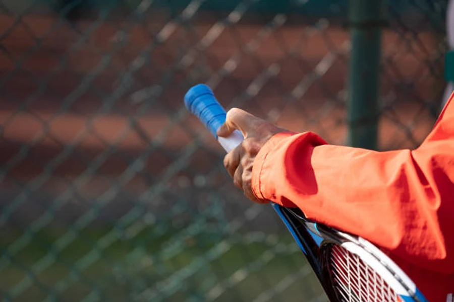 Person greift nach Tennisschläger mit blauem Overgrip