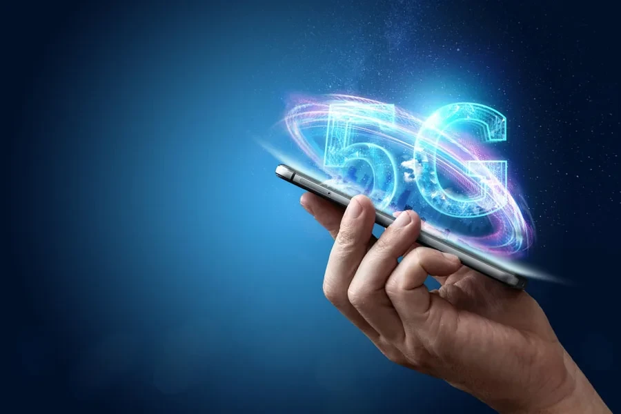 Pessoa segurando um telefone com holograma 5G acima