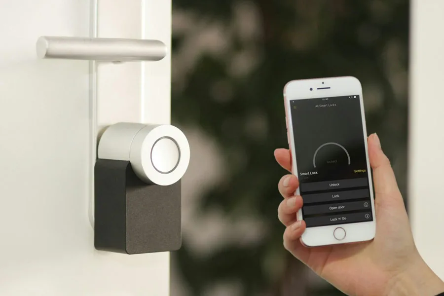 Person holding a smartphone up to a smart lock