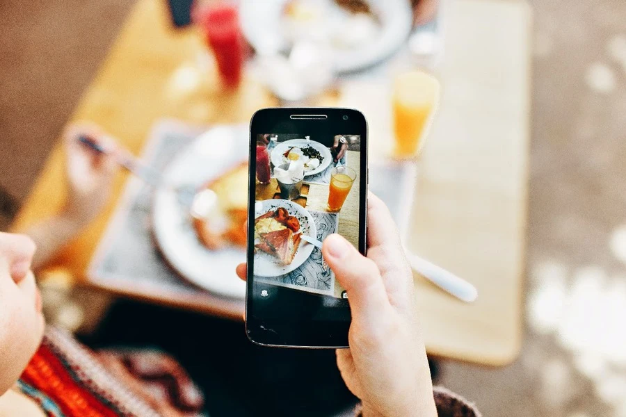 Persona tomando fotografías de la comida servida.