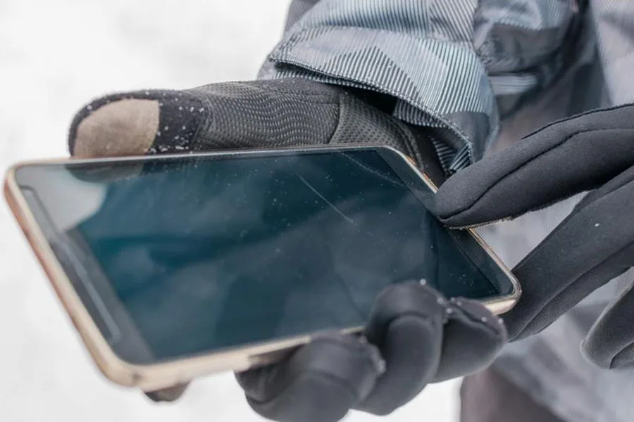 Человек, пользующийся телефоном в перчатках, совместимых с сенсорным экраном