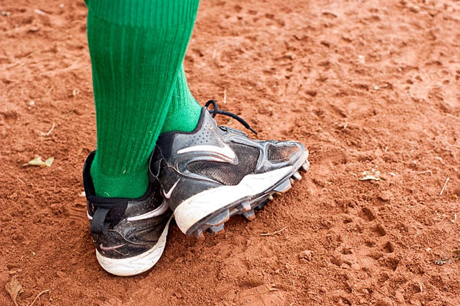 Orang dengan kaus kaki hijau mengenakan sepasang sepatu softball