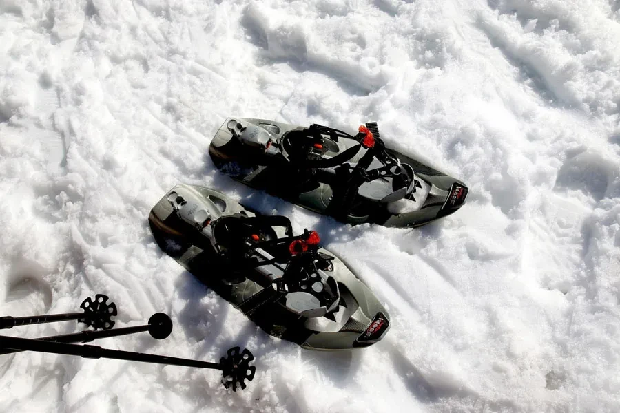 Correre con le racchette da neve accanto ai bastoncini neri per le racchette da neve