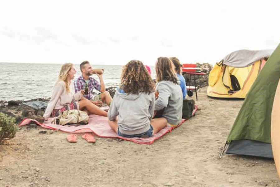 Pequeno grupo sentado na praia ao lado de barracas pop-up