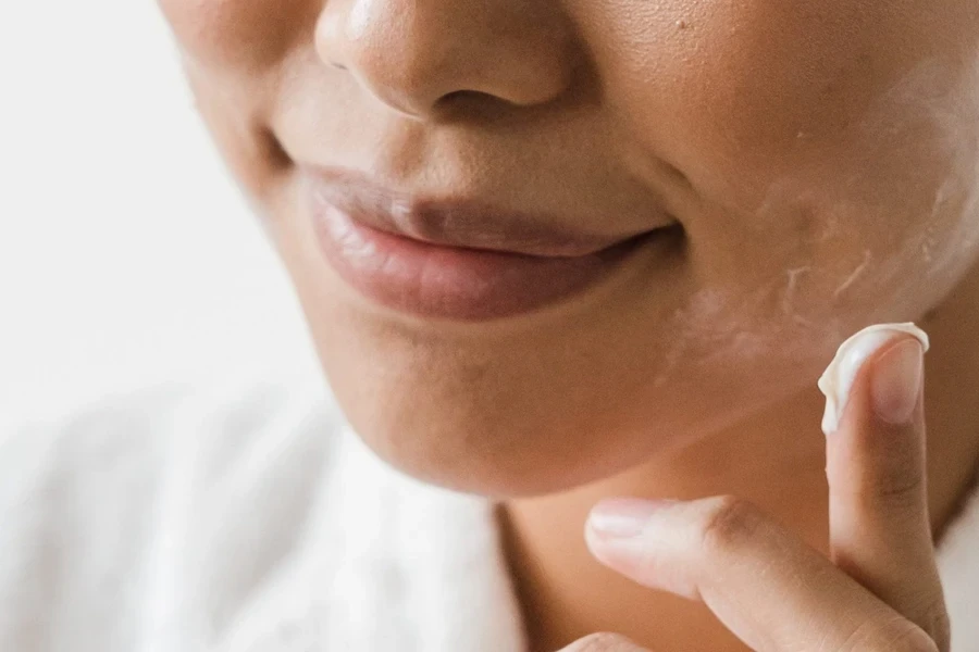 Smiling lady using cream primer on her face