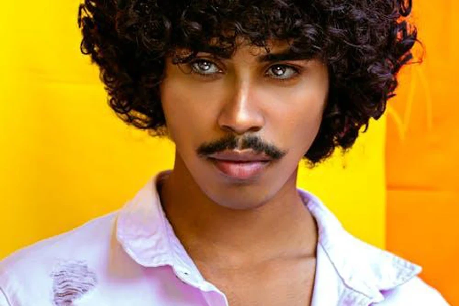 Modelo negro elegante con peinado afro y bigote.