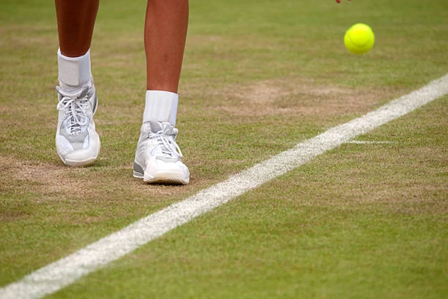 Giocatore di tennis che rimbalza palla sul campo da tennis in erba al basale