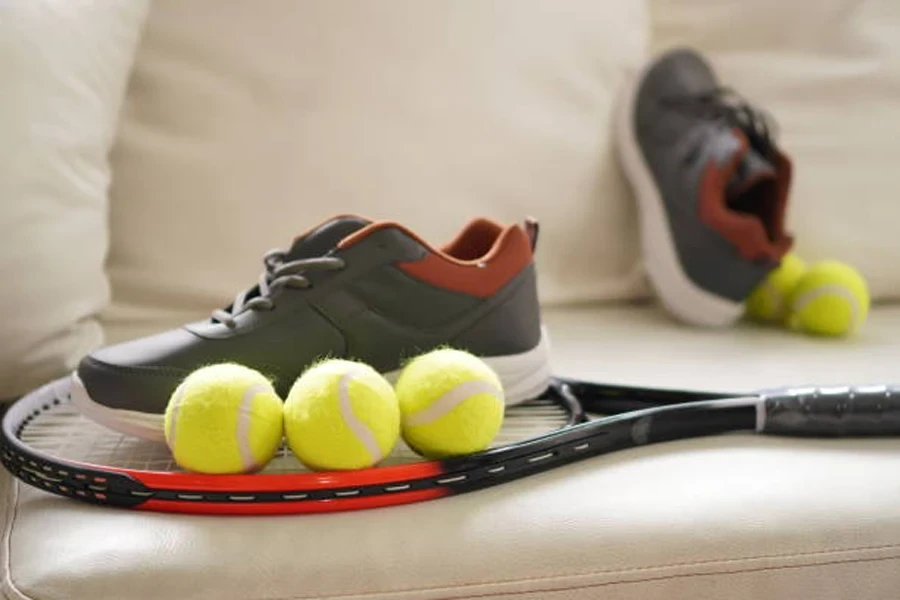 Racchetta da tennis sul divano con scarpe da tennis nere sopra