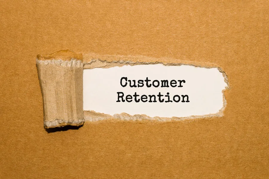 The text “Customer Retention” appearing behind torn brown paper